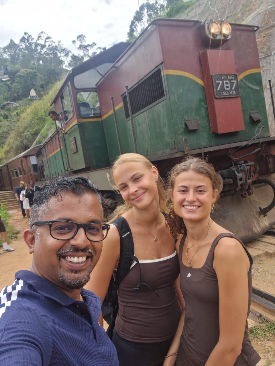 Travellers with driver near a Sri Lankan hill country train