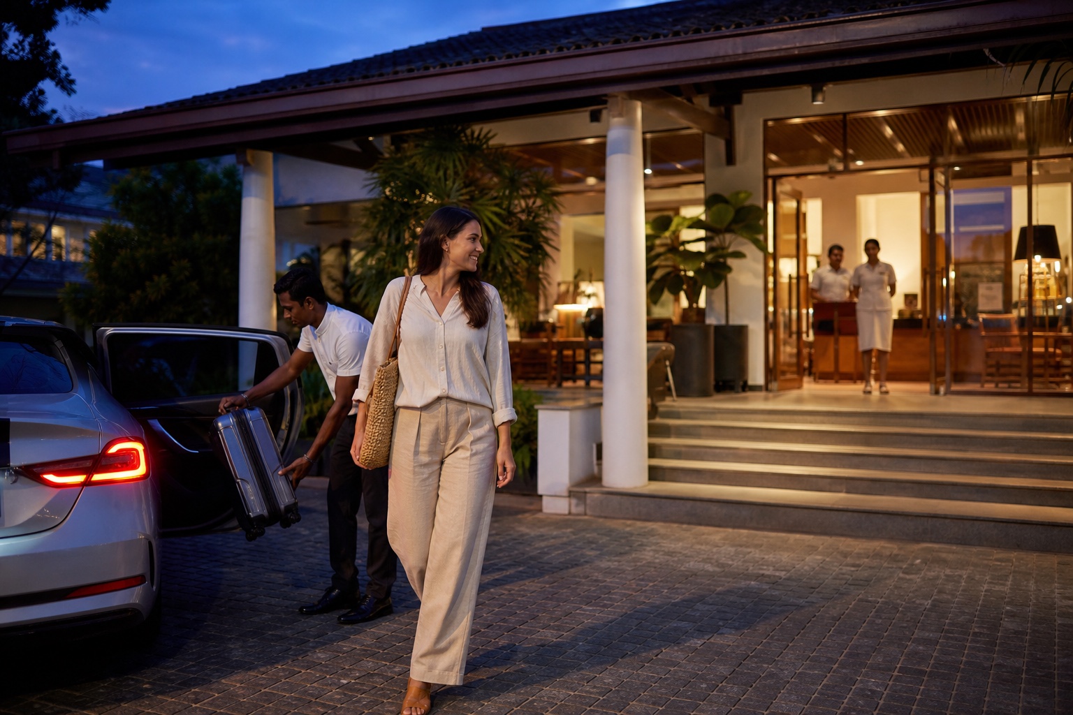 Solo woman traveller arriving with a private driver at a well-lit staffed Sri Lanka hotel in the evening